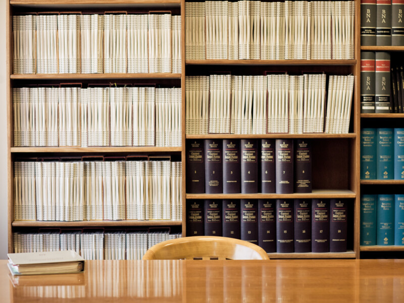 table in front of bookshelf containing legal and regulation reference books