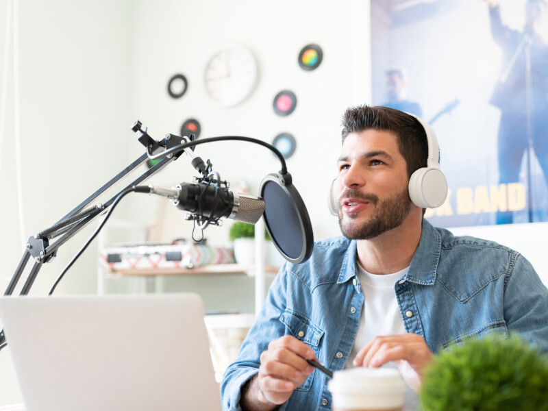 Man with headphones on singing into a studio microphone